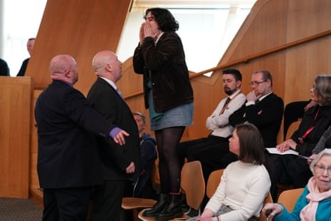 Police and security officers remove a protester from the chamber during FMQs.