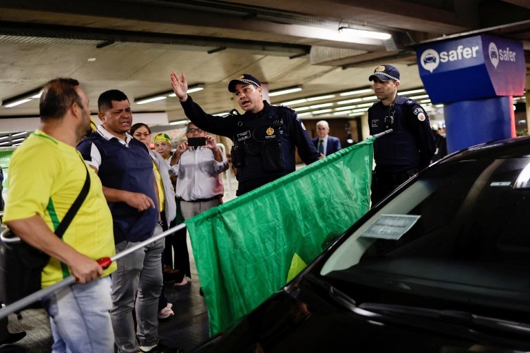 Members of the police forces talk with Bolsonaro supporters while reinforcing security at the airport for the arrival of the former president of Brazil