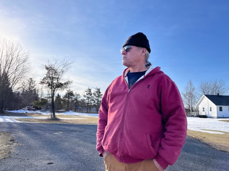 A man standing outside against a winter landscape looks into the distance. 